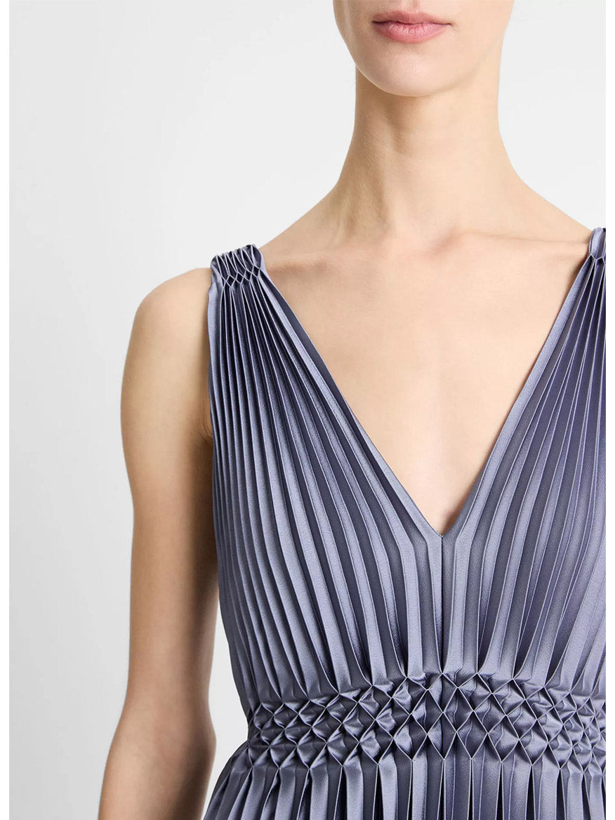Someone wearing the Vince Hand-Smocked Pleated Satin Dress in Mauve Thistle, featuring a sleeveless V-neck design, intricate pleating, and a glossy mauve finish.