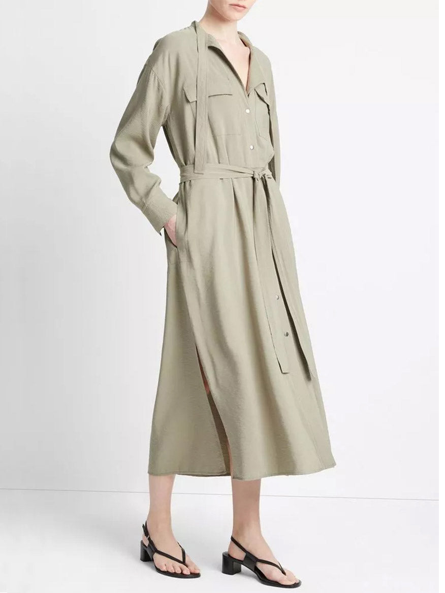 A person wearing a Vince Soft Utility Shirt Dress in Sea Fern with a belt, crafted from responsible materials, and black sandals.