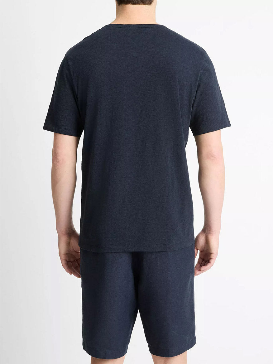 A person is facing away from the camera, wearing the Vince Slub Cotton Split-Neck T-Shirt in Coastal Blue with matching shorts, set against a plain light background.