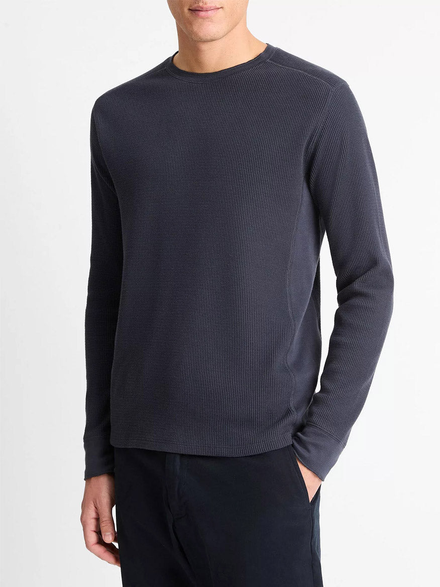 A man wearing a Vince Thermal Long Sleeve Crew Neck Pullover in Coastal Blue and dark pants stands against a plain white background.