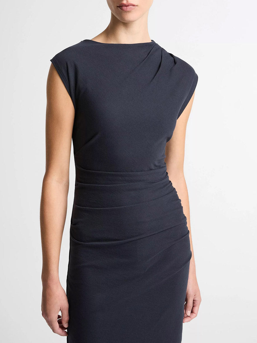 A person wearing the Vince Cotton Twist-Drape Dress in Eclipse, a fitted short-sleeved cotton jersey dress with ruched waist, stands against a plain light background.