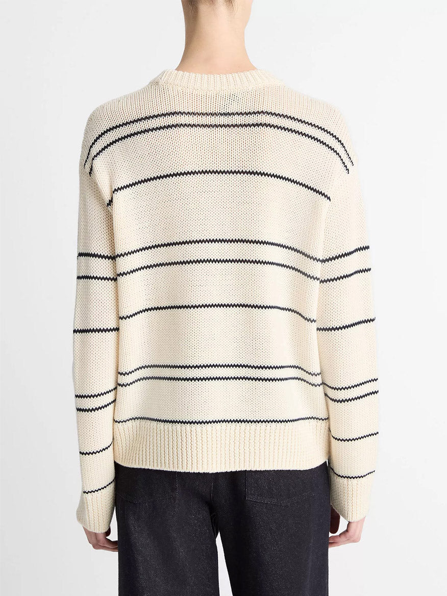 Photographed from behind, the person wears a Vince Variegated Stripe Wool-Blend Sweater in Oat Shell/Navy, styled with dark pants.