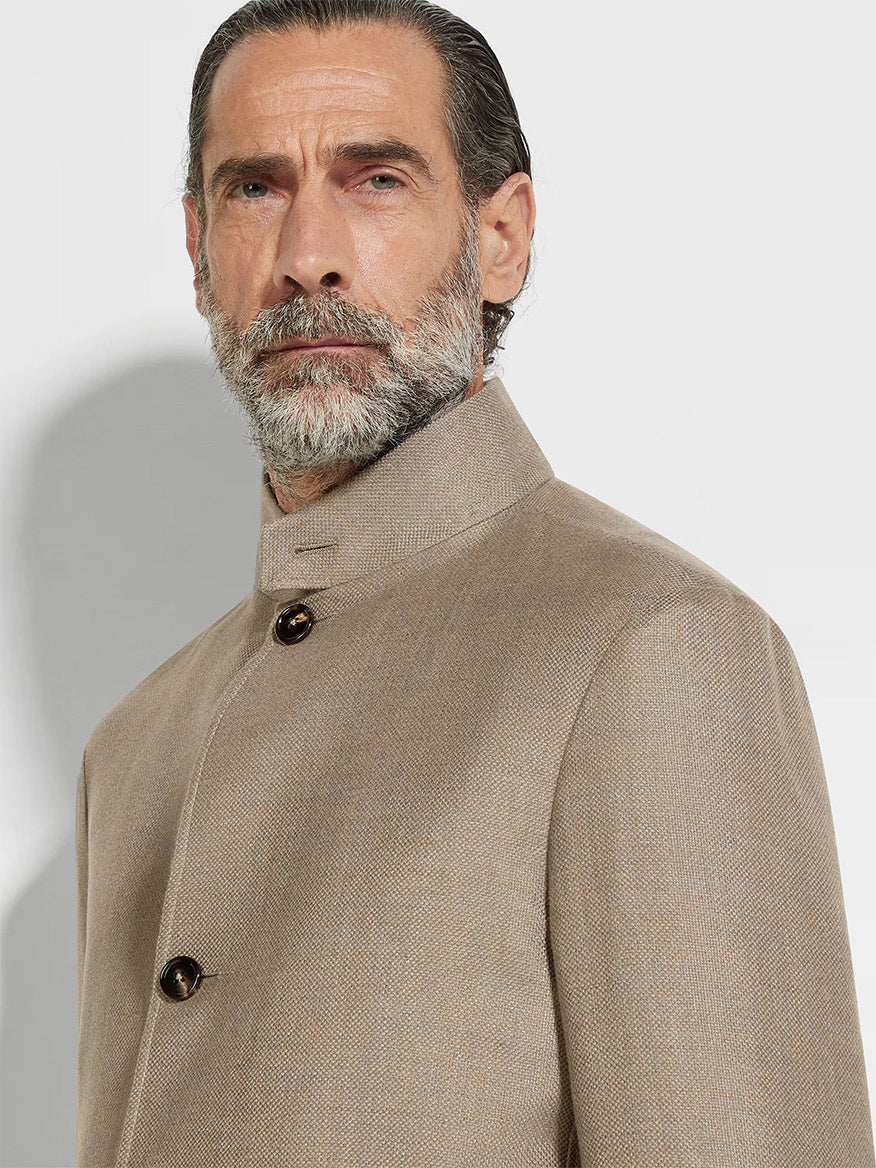 A gray-haired, bearded man wears a Zegna Il Conte Chore Jacket in Light Taupe with a high collar and two visible buttons, looking directly at the camera.