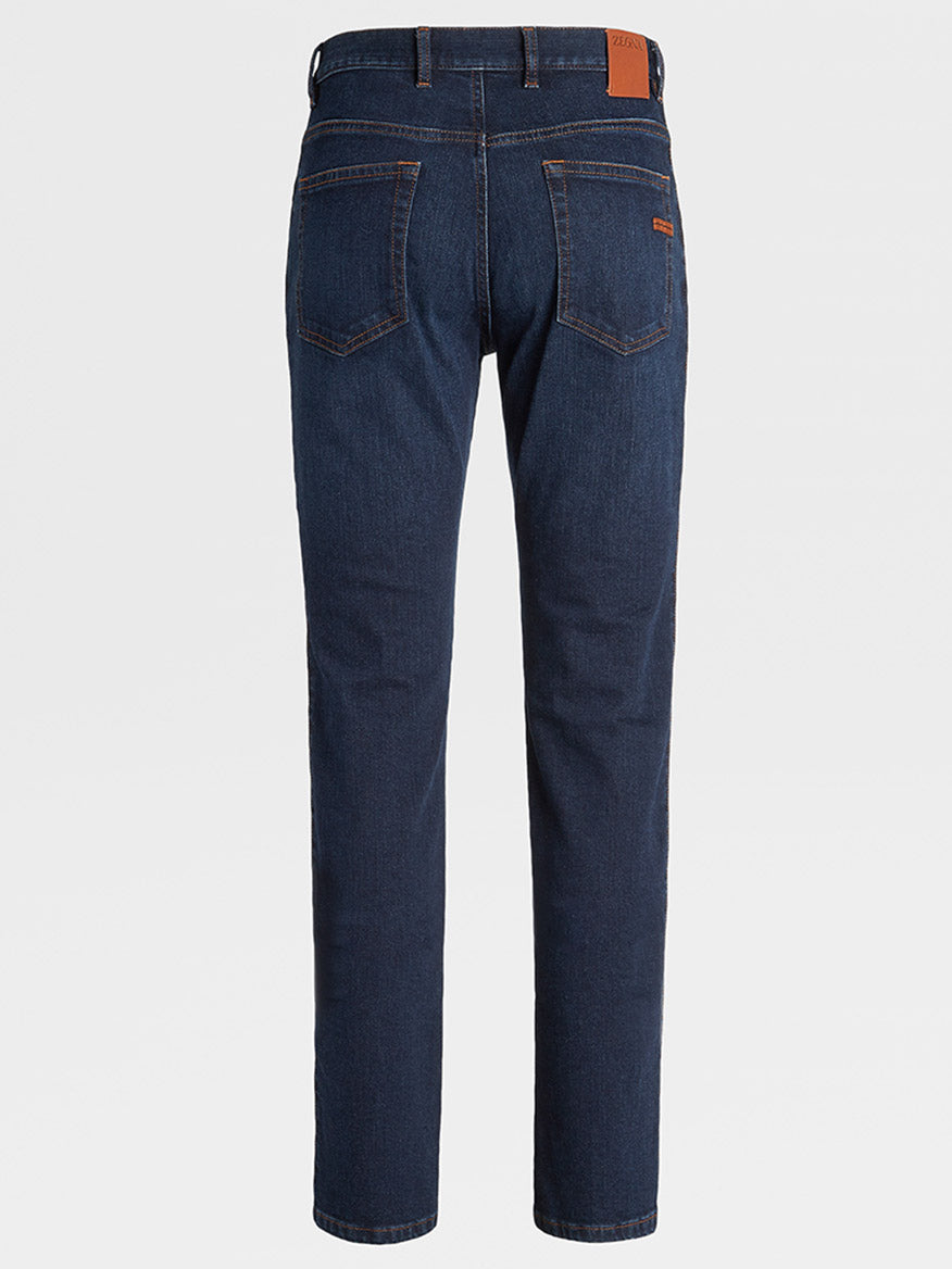 Back view of a pair of Zegna Classic Comfort Cotton Denim in Dark Blue with orange stitching, two back pockets, and a brown leather patch on the waistband. These regular fit jeans offer classic comfort cotton for everyday wear.