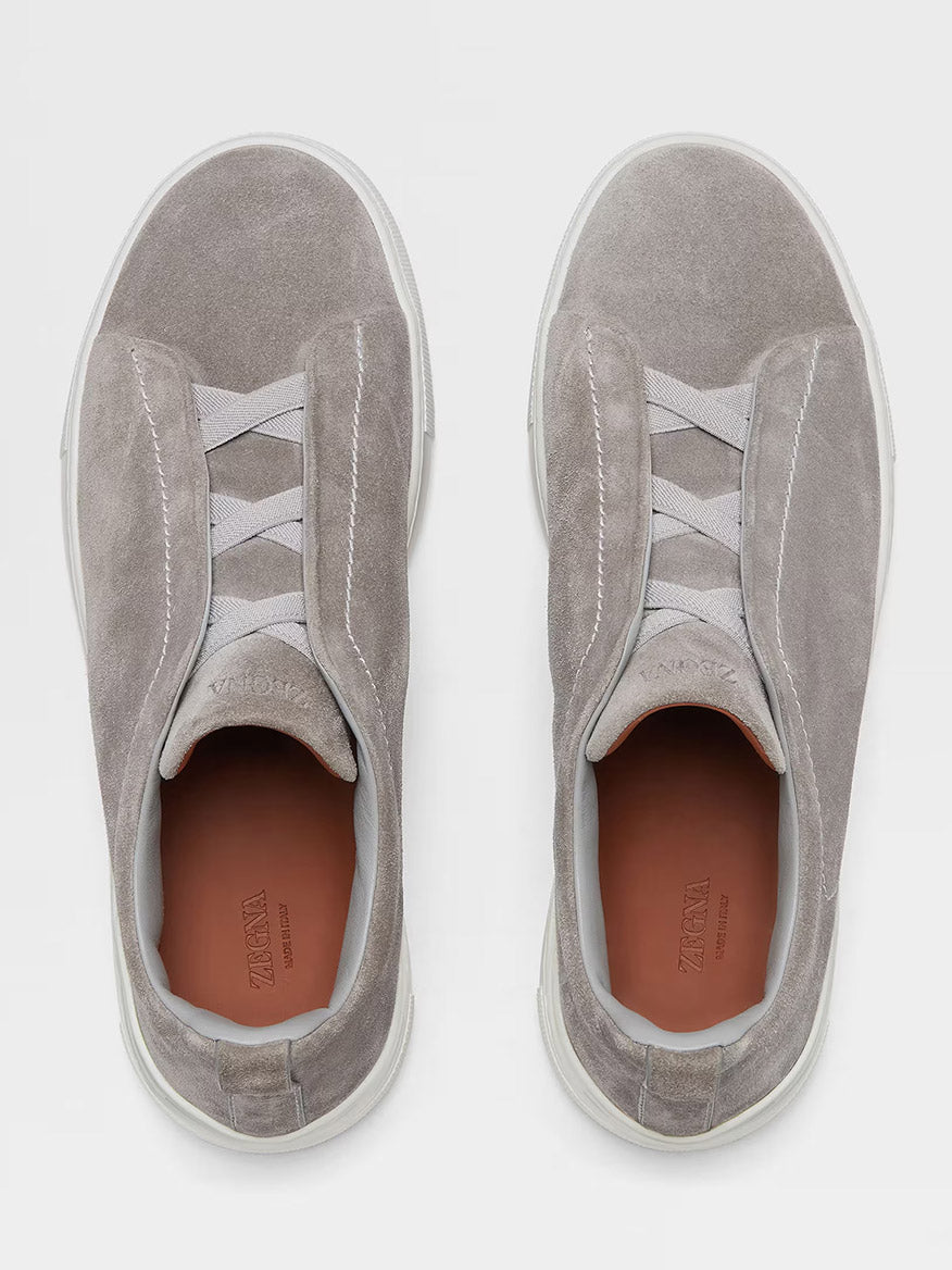 The Zegna Light Grey Suede Triple Stitch™ Sneakers feature lightweight suede, elastic crisscross bands, and white soles, showcasing fine craftsmanship in a stylish silhouette viewed from above.
