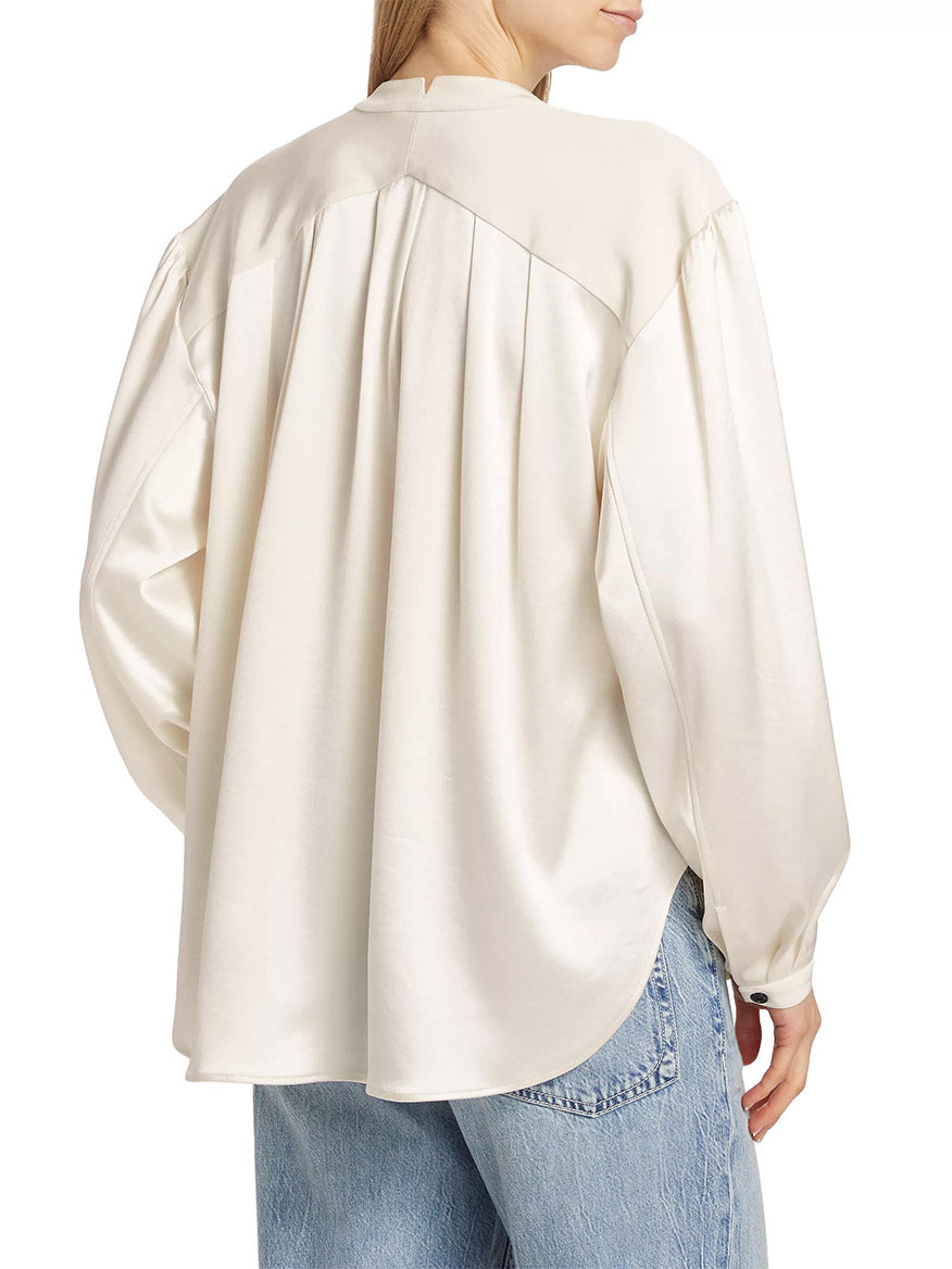 Woman from behind wearing a cream rag & bone Rosie Keyhole Blouse in Ivory with detailed pleating on the back, paired with blue jeans.