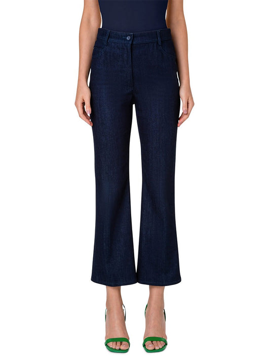 A person wearing Akris Punto Cali Stretch Crop Bootcut Denim in Dark Blue and green open-toe heels, standing against a white background.