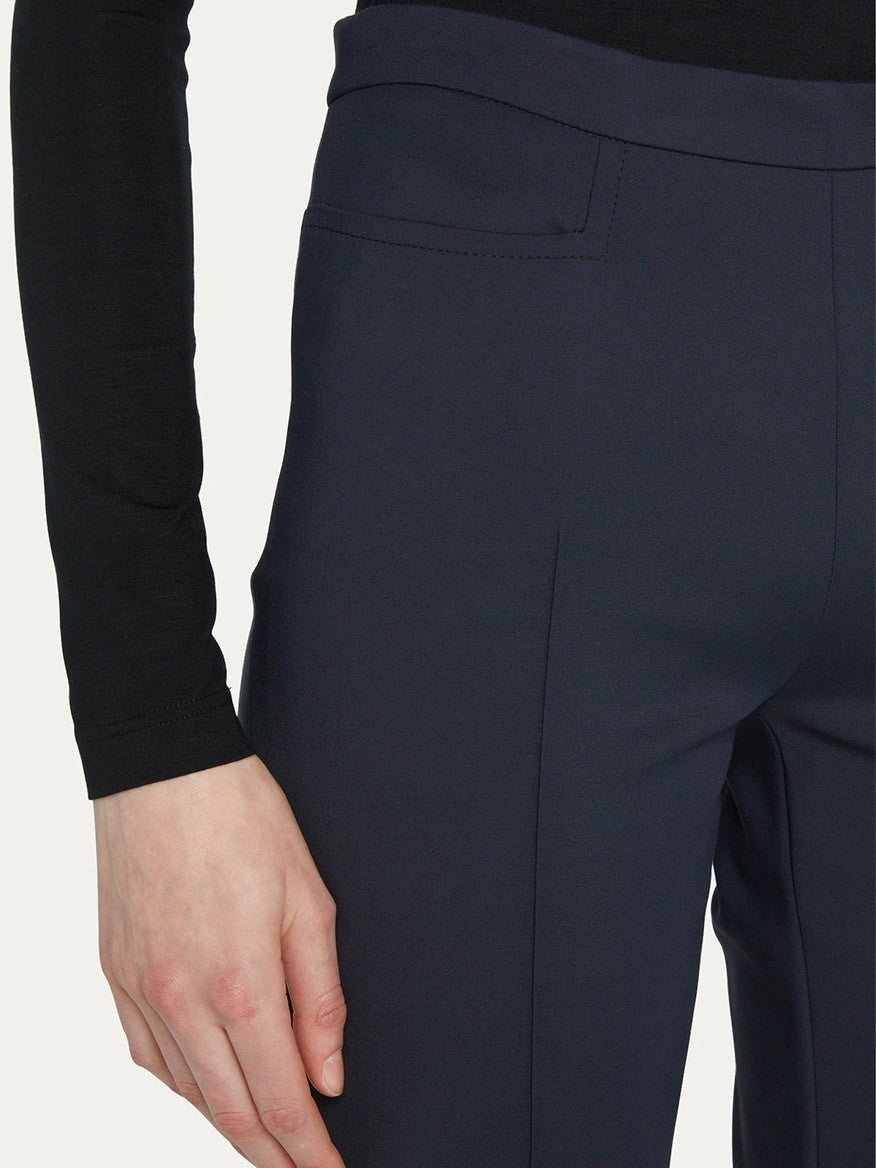 Close-up of a person wearing Akris Punto Franca Mid-Rise Ankle Pants in navy and a black long-sleeve shirt, highlighting the side seam and pocket area of the slim-cut legs made from a techno cotton blend.