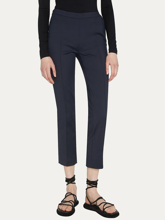 Person wearing a long-sleeve black shirt, Akris Punto Franca Mid-Rise Ankle Pants in Navy with slim-cut legs, and black strappy sandals.