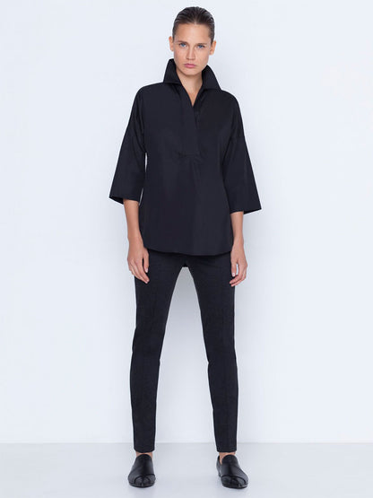 A model wearing Akris Punto Mara Stretch Jersey Pants in Black paired with a black shirt with a structured collar and flat shoes against a white background.