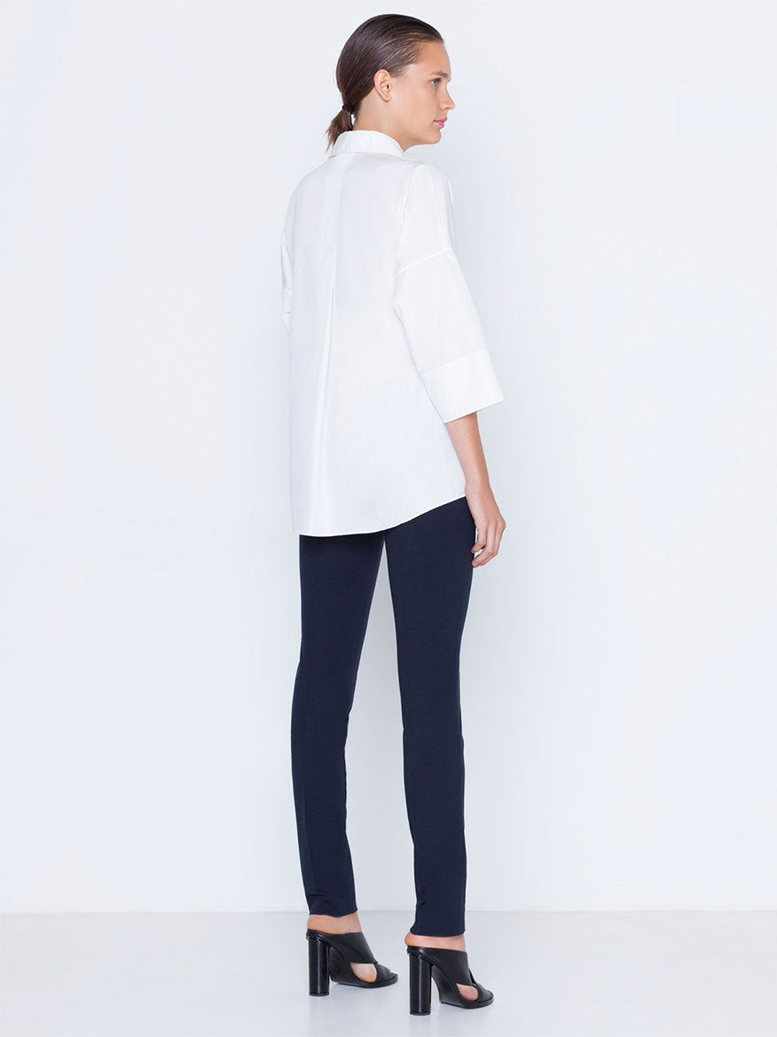 Woman standing in profile wearing a white shirt and Akris Punto Mara Stretch Jersey Pants in Navy with front zip closure.