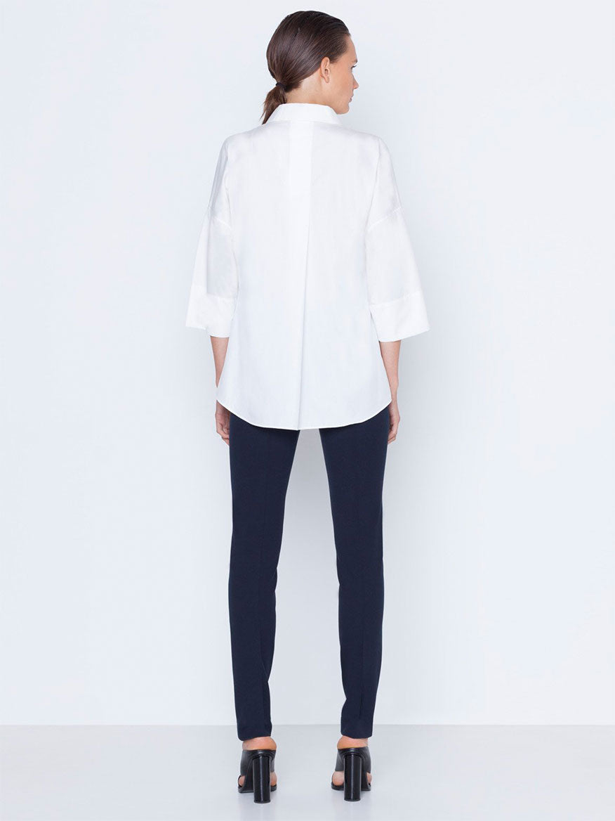 Woman standing with her back to the camera, wearing a white blouse and the Akris Punto Mara Stretch Jersey Pants in Navy.