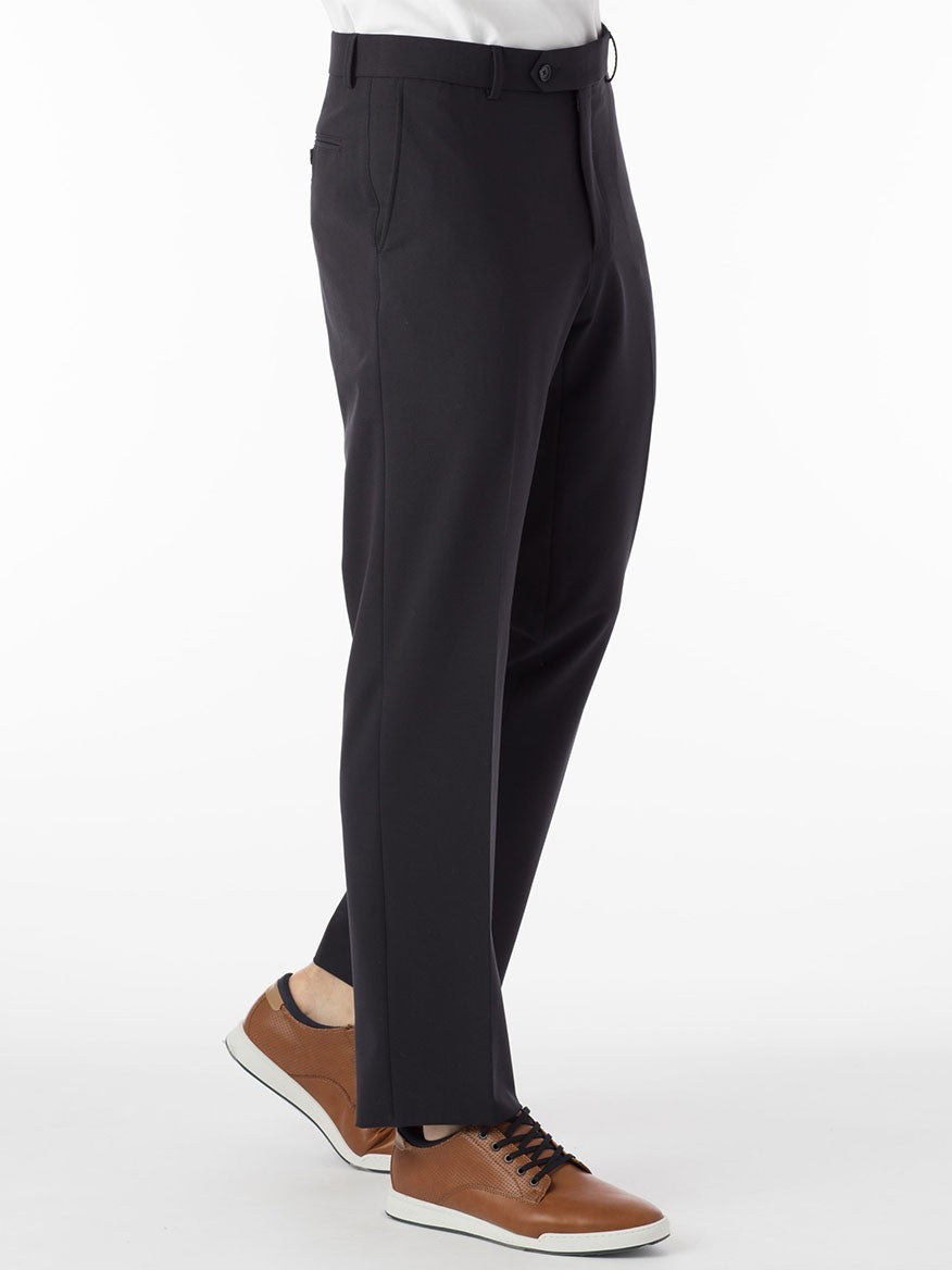 A person wearing navy modern flat front pants with a comfort "EZE" waistband and brown sneakers stands on a white background.