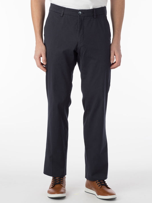 A person wearing navy Ballin Atwater True Khaki Modern Flat Front Pants and a white shirt stands against a plain white background. Only the lower torso and legs are visible.