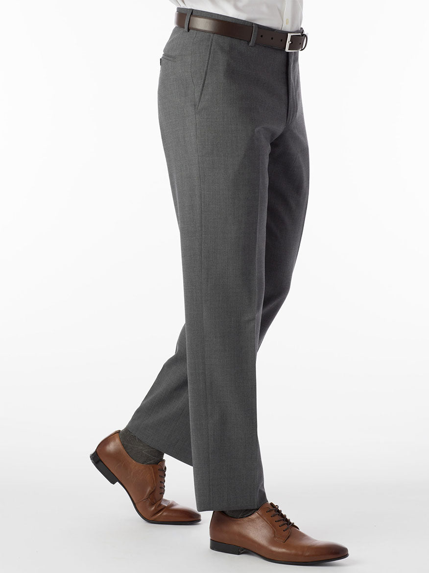 A man in a gray suit is standing on a white background, showcasing the durability and comfort of the Ballin Soho Comfort 'EZE' Super 120s Modern Flat Front Twill Pant in Mid Grey fabric.