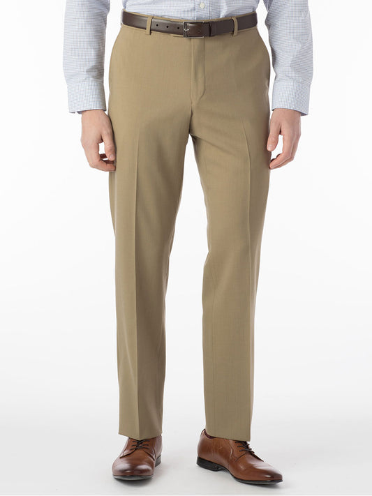 A person stands against a white background wearing Ballin Soho Comfort 'EZE' Super 120s Modern Flat Front Twill Pant in Sand, a brown belt, light blue button-up shirt, and brown dress shoes.