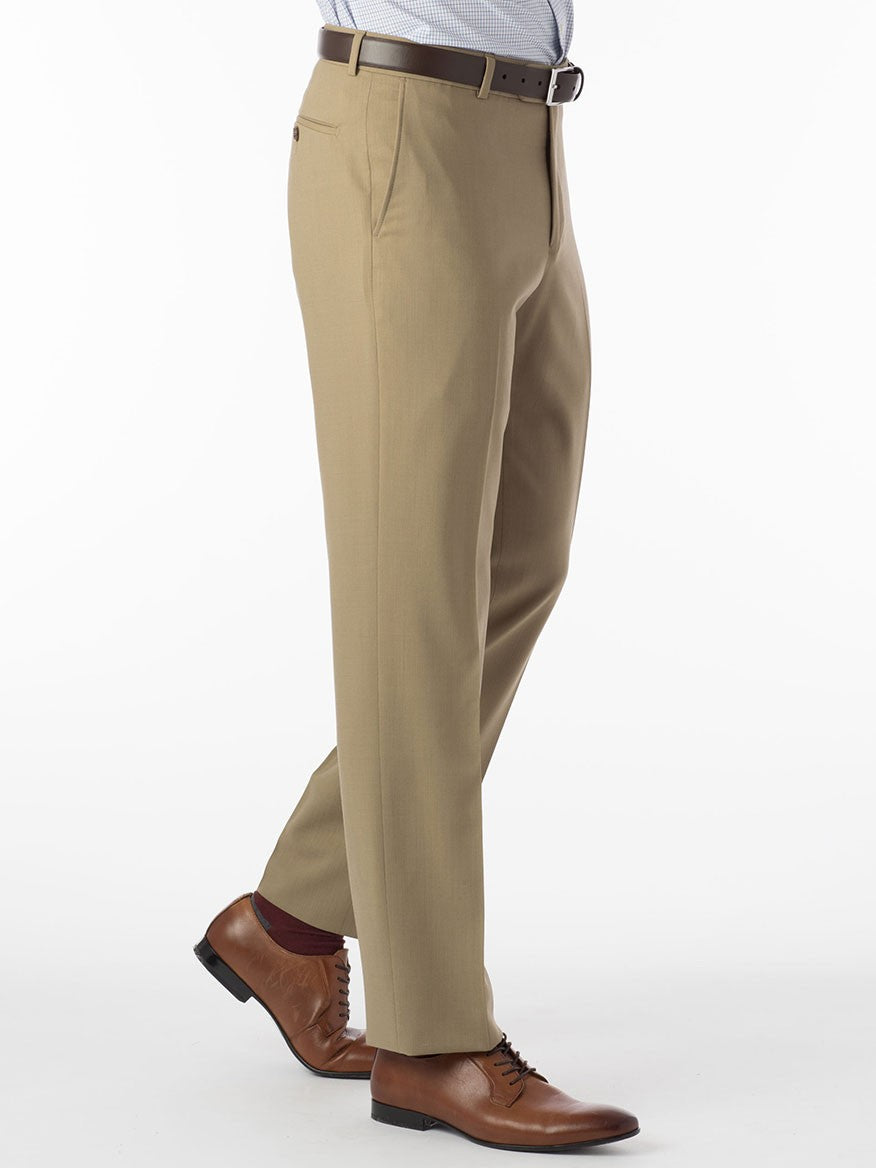 A person in Ballin Soho Comfort 'EZE' Super 120s Modern Flat Front Twill Pant in Sand, paired with a brown belt and brown dress shoes, stands with one leg slightly forward against a white background.