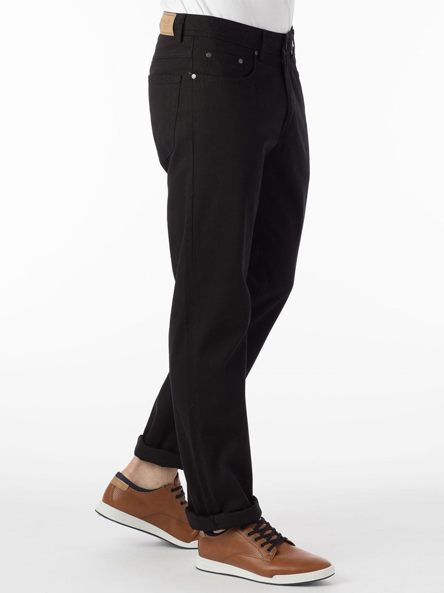 A man wearing Ballin Crescent Modern 5 Pocket Twill Pants in Black jeans and a white pima cotton t-shirt.