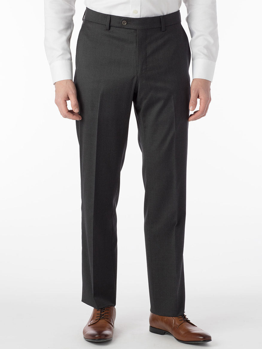 A man is standing in a Ballin Houston Super 130s Modern Flat Front Pant in Charcoal suit with brown shoes, showcasing sartorial details.