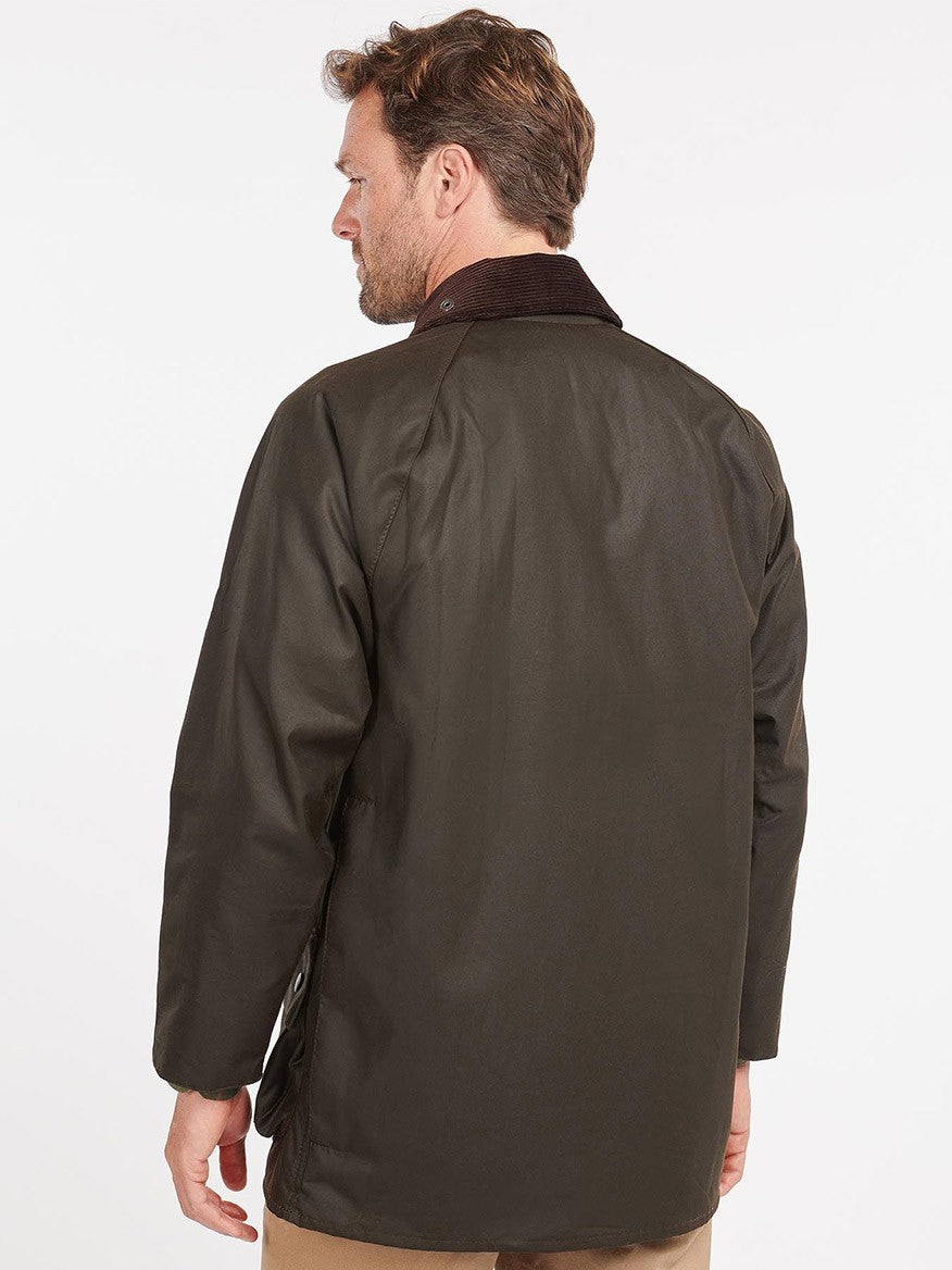 Rear view of a man wearing a dark brown Barbour Classic Beaufort in Olive jacket with a collar, standing against a plain background.