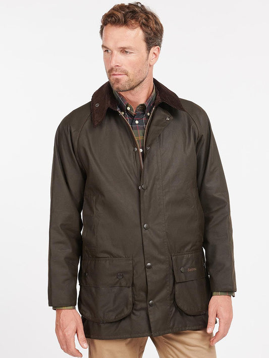 Man wearing a dark olive green Barbour Classic Beaufort jacket with a brown corduroy collar, standing against a light background.
