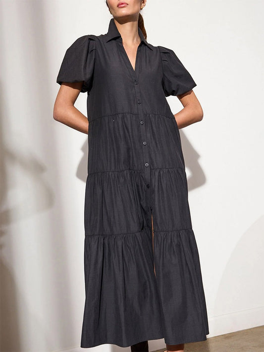 A person modeling a versatile, dark-colored, short-sleeved Brochu Walker Havana Dress in Washed Black with button-up front and tiered skirt design.