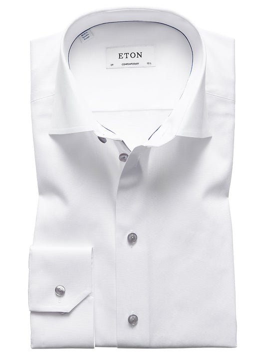 A neatly folded Eton Contemporary Fit White Twill Dress Shirt with grey details, featuring a visible label printed with the word "ETON," showcasing the collar and buttons.