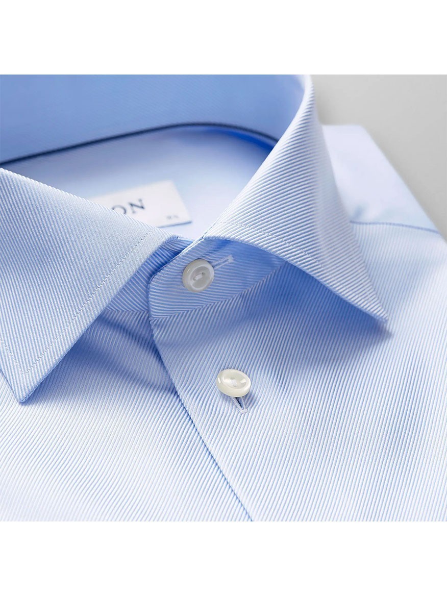 Close-up of the Eton Slim Fit Light Blue Textured Twill Dress Shirt, featuring a spread collar and white buttons—expertly folded and ideal for sharp business attire.