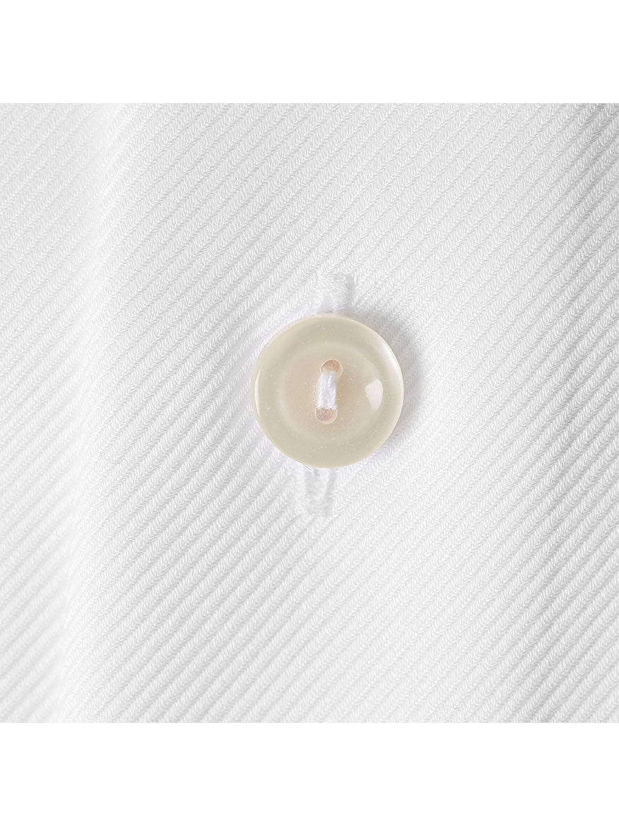 Close-up of a white button on textured fabric with diagonal lines—showcasing the perfect detail of the Eton Slim Fit White Twill French Cuff Dress Shirt.