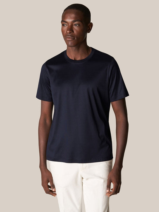 A man wearing an Eton Filo di Scozia T-Shirt in Navy and white pants stands against a neutral background.