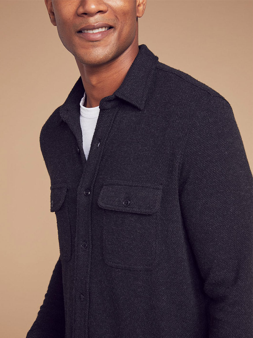 A man wearing a versatile dark grey Legend™ Faherty Brand Sweater Shirt in Heather Black Twill over a comfortable white t-shirt, half-smiling at the camera.