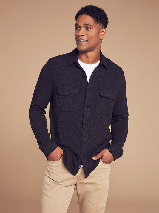 Man in a Faherty Brand Legend Sweater Shirt in Heather Black Twill and light pants posing with hands in pockets.