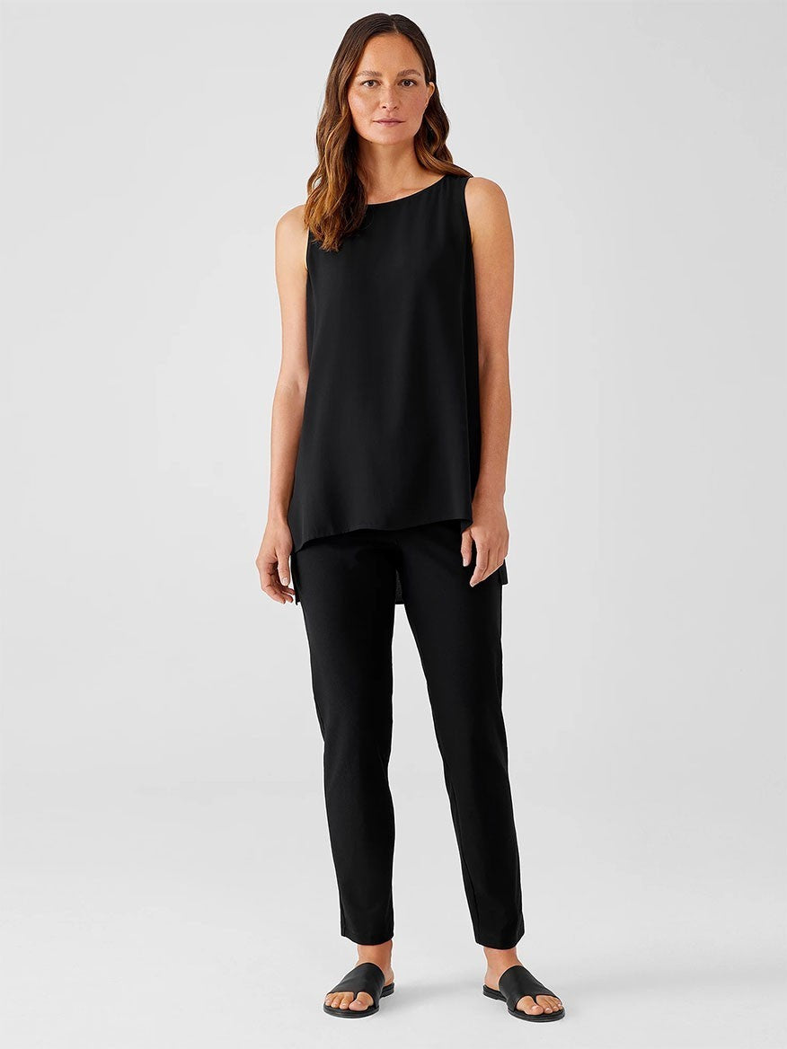 Woman wearing a black sleeveless top and Eileen Fisher Washable Stretch Crepe Pant in Black, standing against a neutral background.