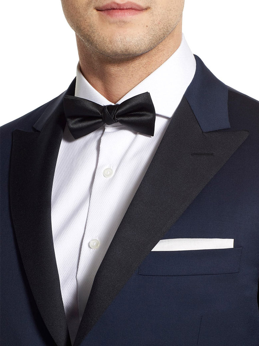 Dressed in a Hickey Freeman (Heritage Gold) Navy Tasmanian Wool Tuxedo, complete with a white shirt, black bow tie, peak lapel, and pocket square, one elegantly showcases the craftsmanship of this exquisite garment.