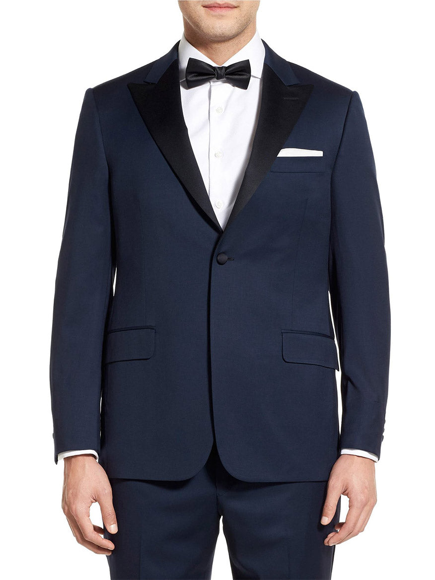 A person dressed in a Hickey Freeman (Heritage Gold) Navy Tasmanian Wool Tuxedo featuring peak lapels, accessorized with a black bow tie and a white shirt.