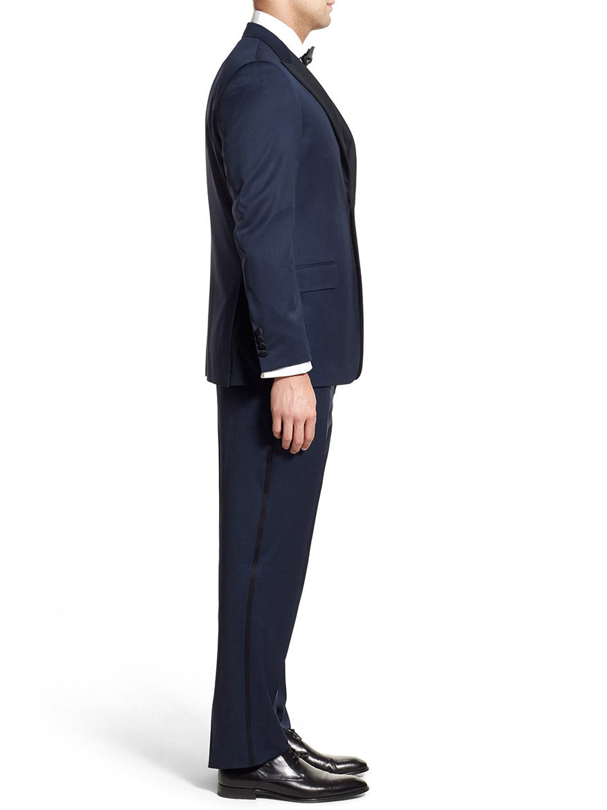 A person in a Hickey Freeman (Heritage Gold) Navy Tasmanian Wool Tuxedo with a peak lapel stands in profile against a white background.