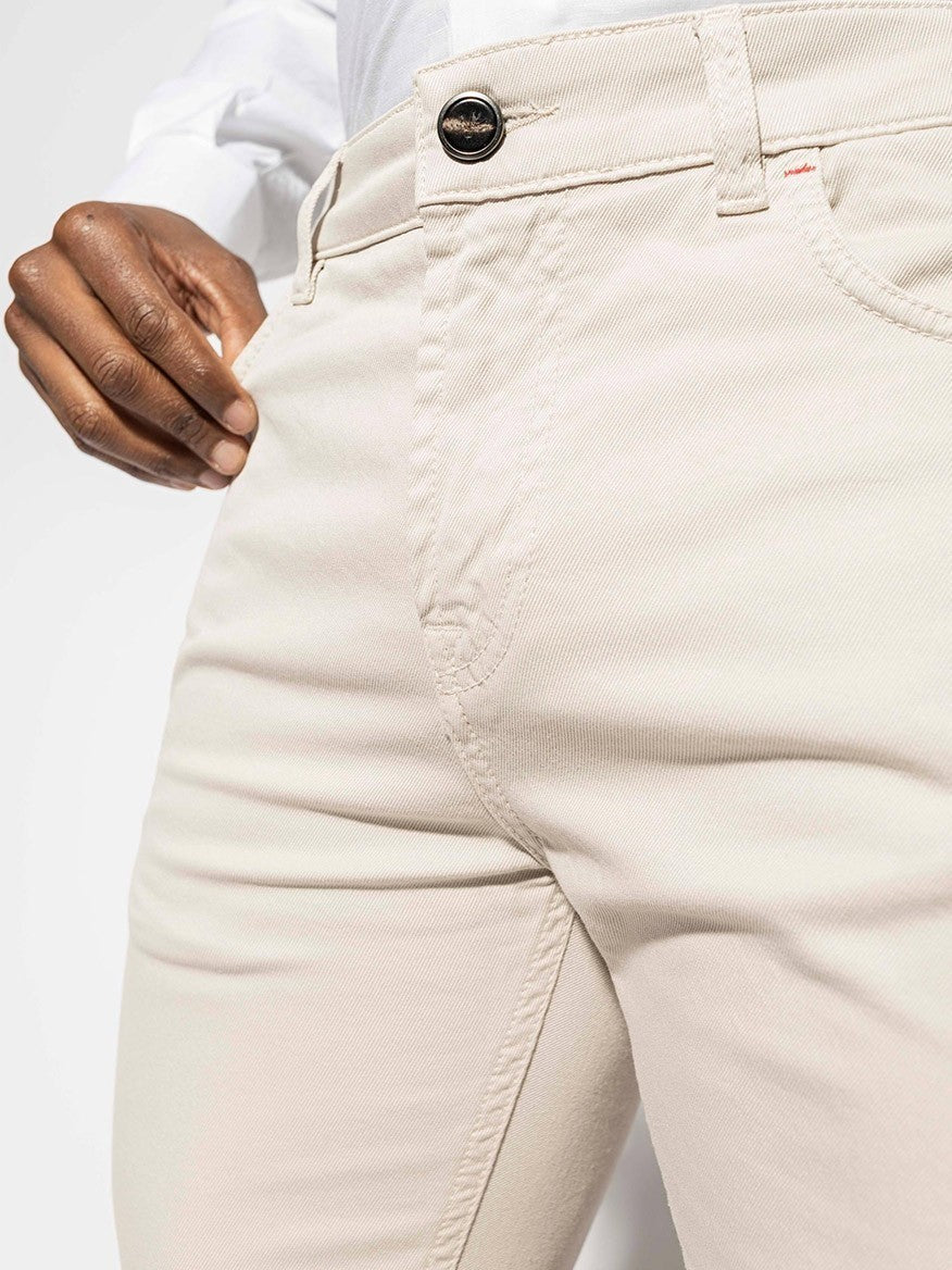 A man wearing Isaia Slim Straight 5-Pocket Denim jeans in Stone with a white shirt.