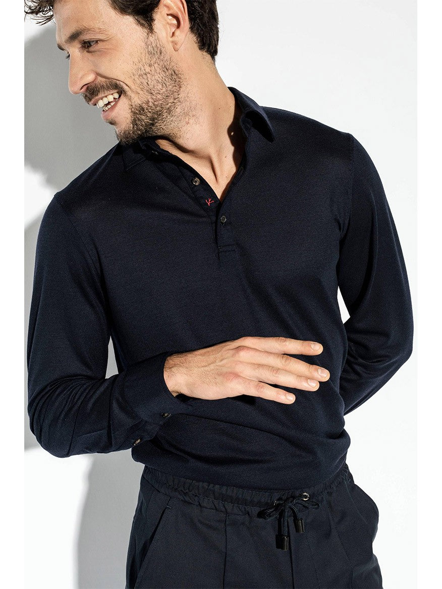 A man wearing a long-sleeve, dark-colored Isaia Evening Polo in Navy and dark drawstring pants smiles while looking to his right.