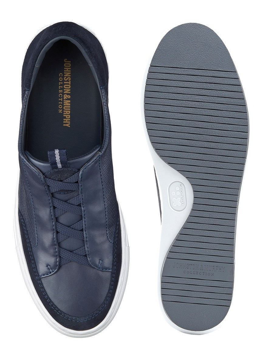 A pair of J & M Collection Anson Stretch Lace-to-Toe Navy English Suede/Sheepskin with white soles featuring cushioning for added comfort.