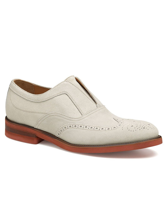 A single J & M Collection Ashford Wingtip Slip-On in Bone Italian Suede with perforated detailing.
