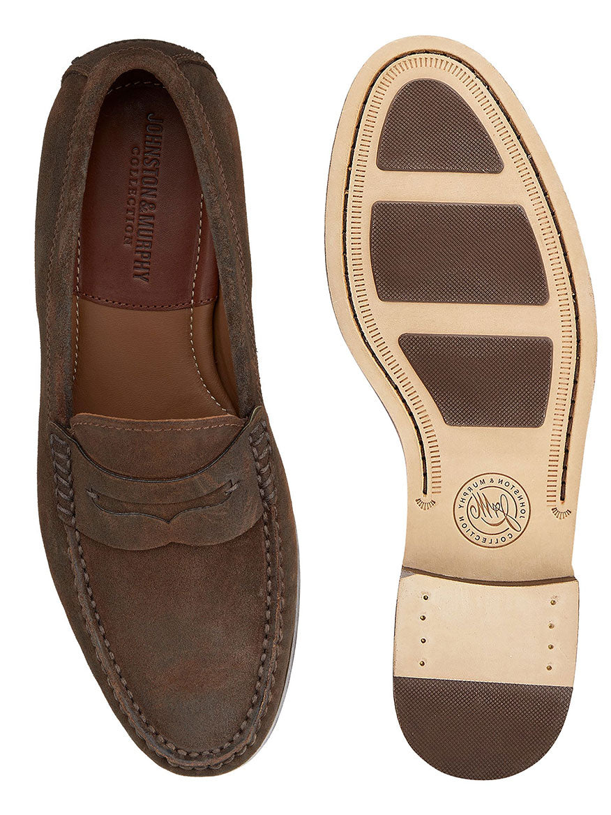 A pair of J & M Collection Baldwin Penny in Brown Waxed English Suede is shown. One shoe is displayed from the top, and the other from the bottom, highlighting the sole's design and brand markings. The handmade moccasin features a cushioned footbed and leather lining for ultimate comfort.