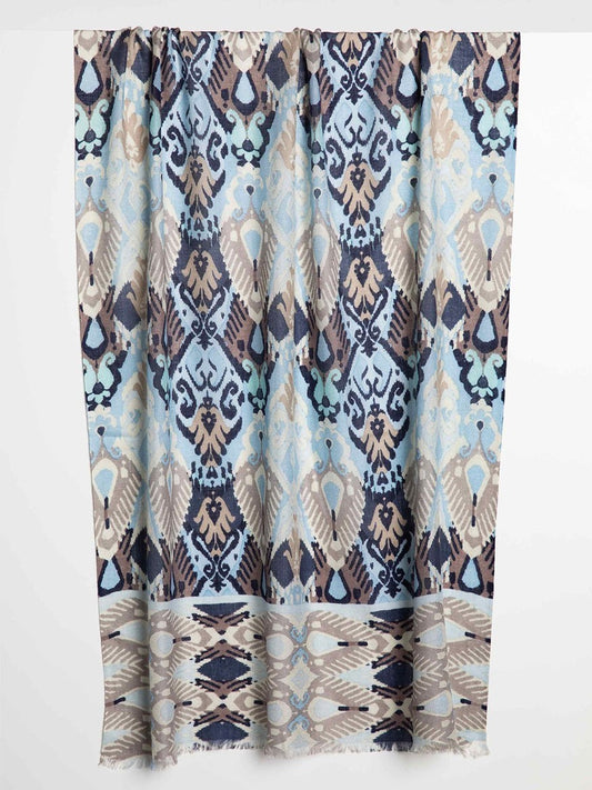 Patterned fabric with the Kinross Oceana Ikat Print Scarf in Coastal Multi hanging vertically.
