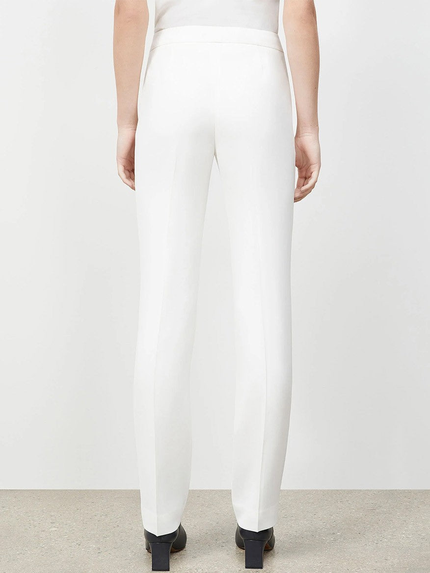 Back view of a person wearing expertly tailored white Lafayette 148 New York Finesse Crepe Barrow Pant in Cloud and black high heels, standing on a neutral colored floor against a white background.