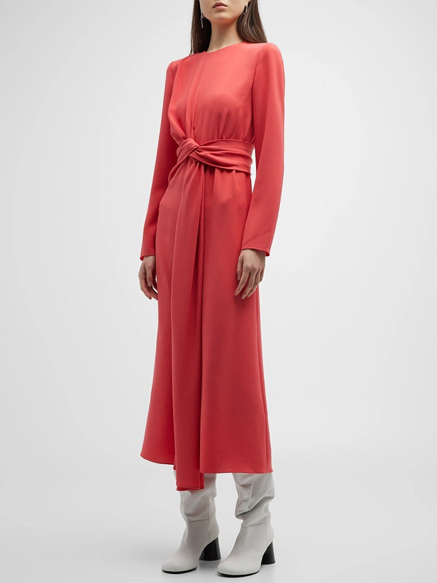 A person stands in a Lafayette 148 New York Finesse Crepe Twist Dress in Coral, paired with white ankle boots against a plain background.