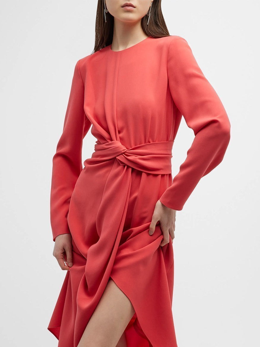 A person wearing a Lafayette 148 New York Finesse Crepe Twist Dress in Coral with long sleeves, featuring a front twist at the waist and a thigh-high slit. The background is plain white.