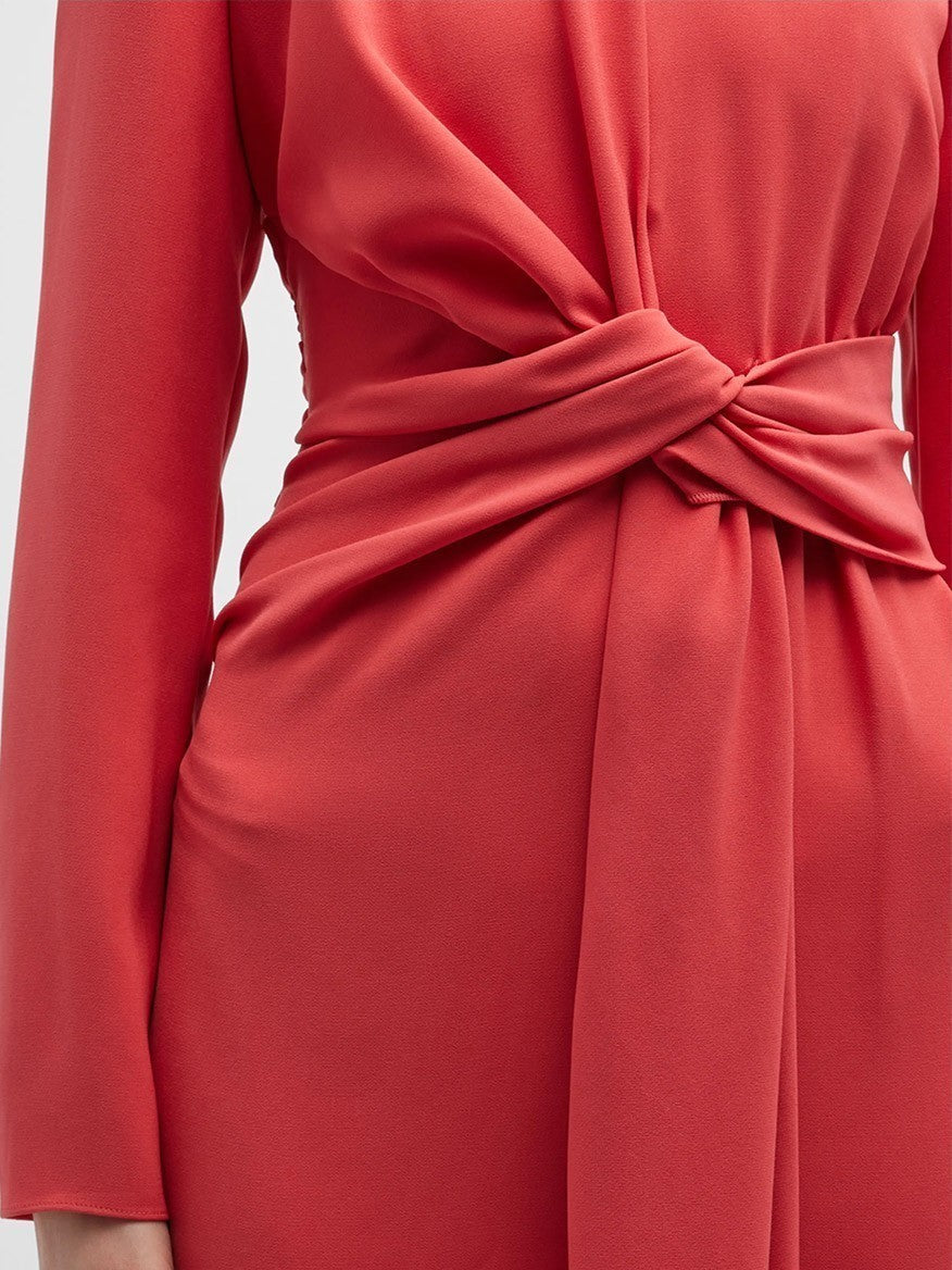 Close-up of a person wearing a long-sleeved, coral-colored Lafayette 148 New York Finesse Crepe Twist Dress in Coral with a front twist at the waist.