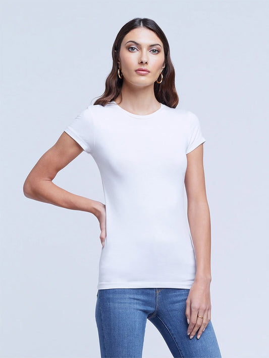 Woman posing in a L'Agence Ressi Short Sleeve Crew in White and blue jeans against a gray background.