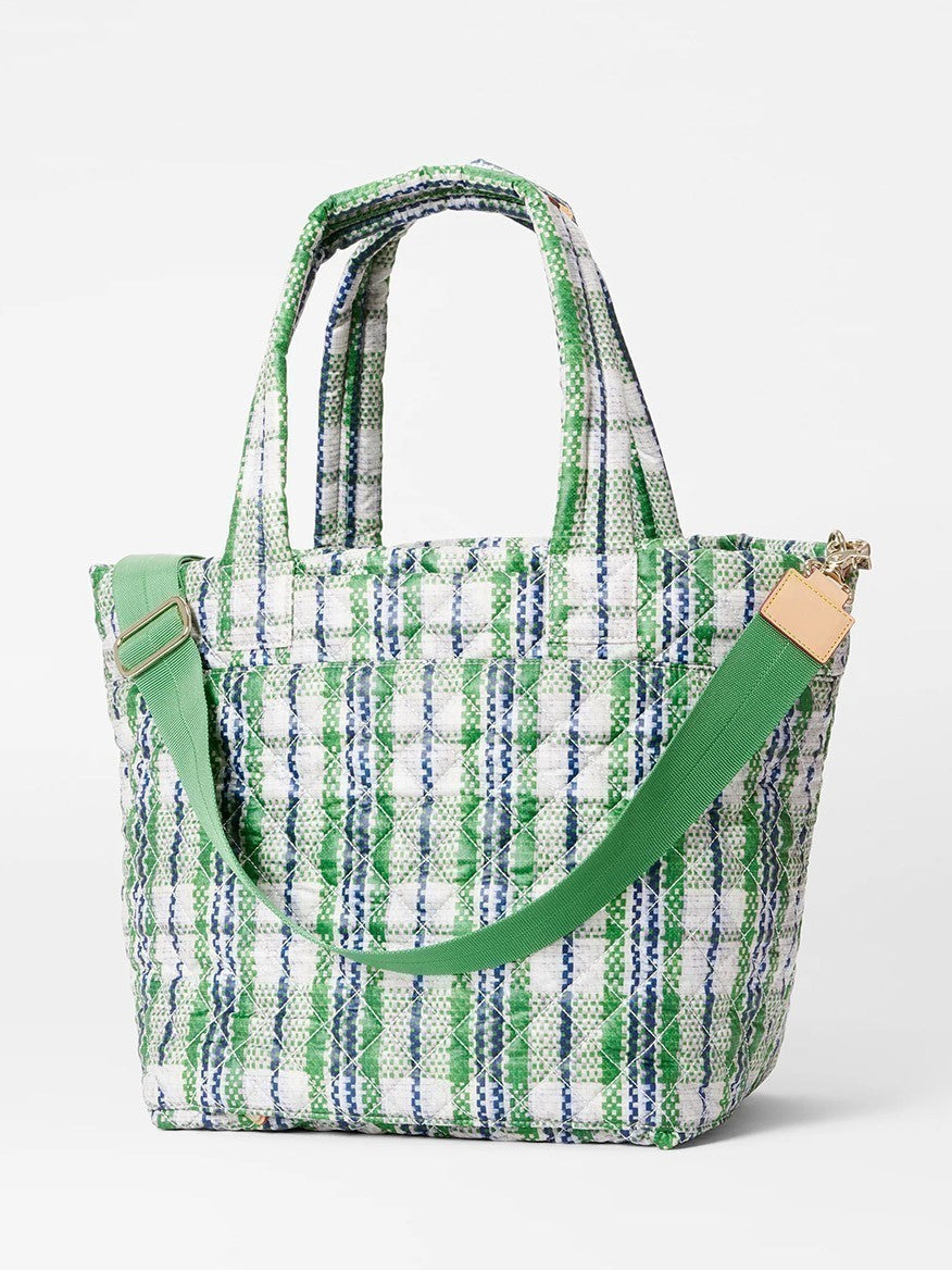 A MZ Wallace Medium Metro Tote Deluxe in Spring Plaid Oxford in white, green, and blue with a green shoulder strap and tan leather accents, crafted from REC Oxford fabric, displayed against a white background.