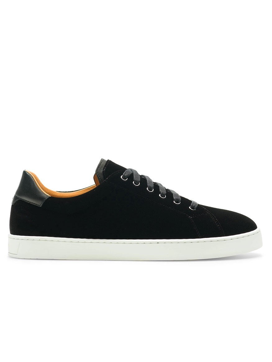 The Magnanni Dalia II in Black is a black low-top sneaker with black laces, white sole, orange inner lining, and a black heel tab, displayed in side profile against a white background.