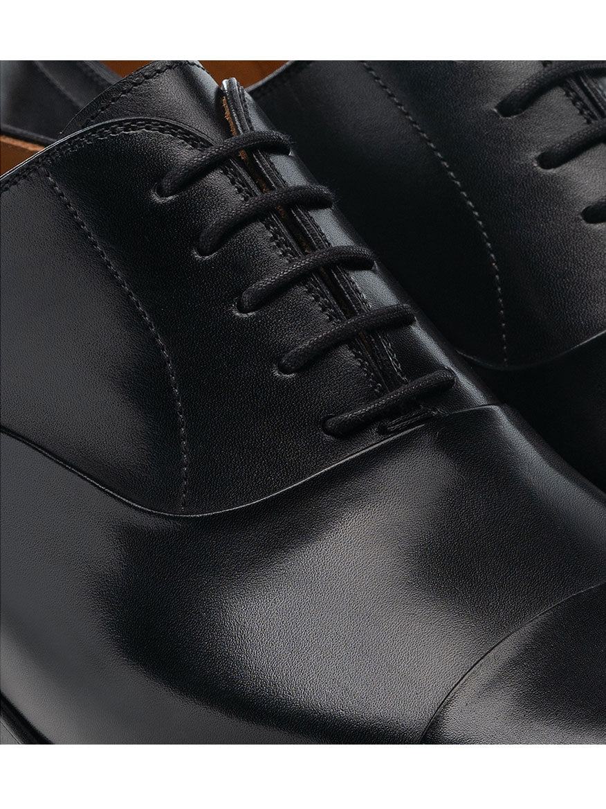 Close-up view of a pair of polished Magnanni Segovia in Black calfskin leather dress shoes with black laces.